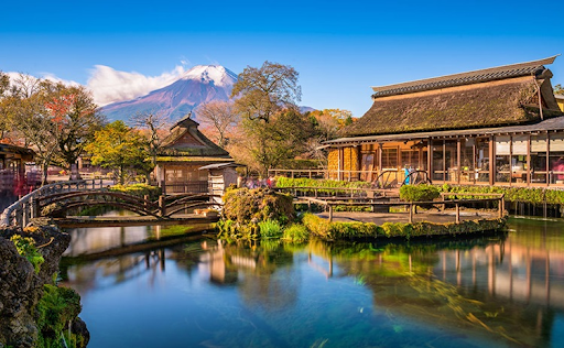 A picture of Oshino Hakkai with a view of the village houses, the lake, and Mount Fuji.